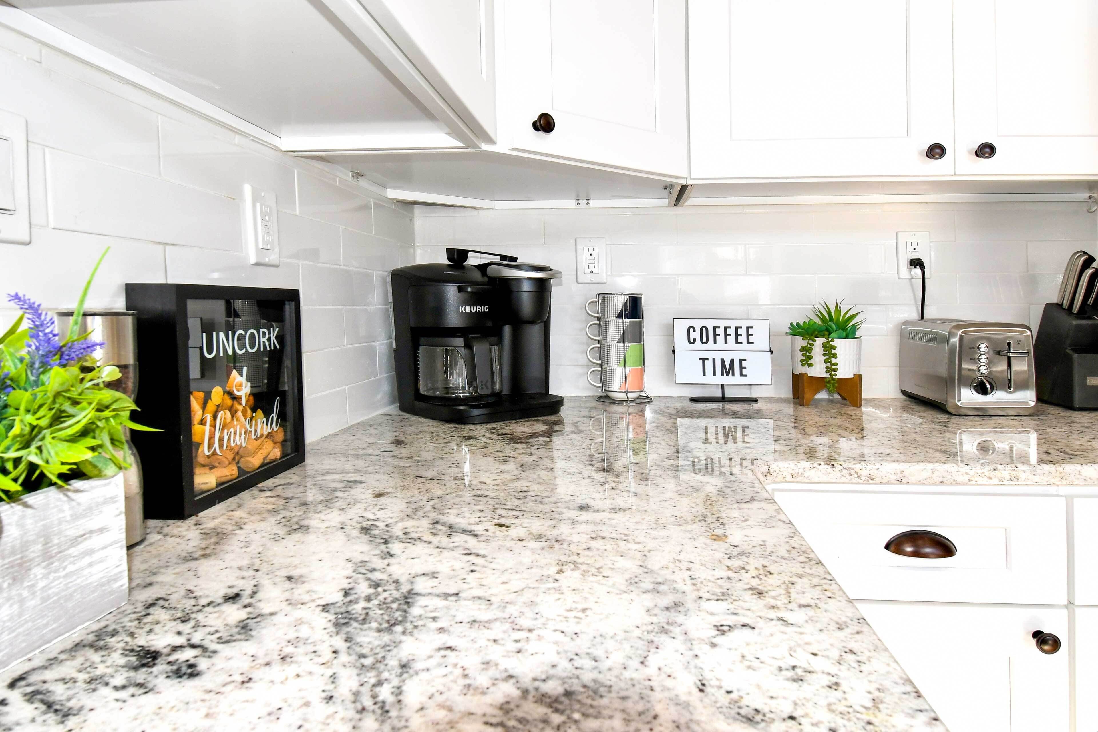 Una cucina moderna con mobili bianchi, una macchina da caffè, un tostapane e un cartello con scritto 'COFFEE TIME'.