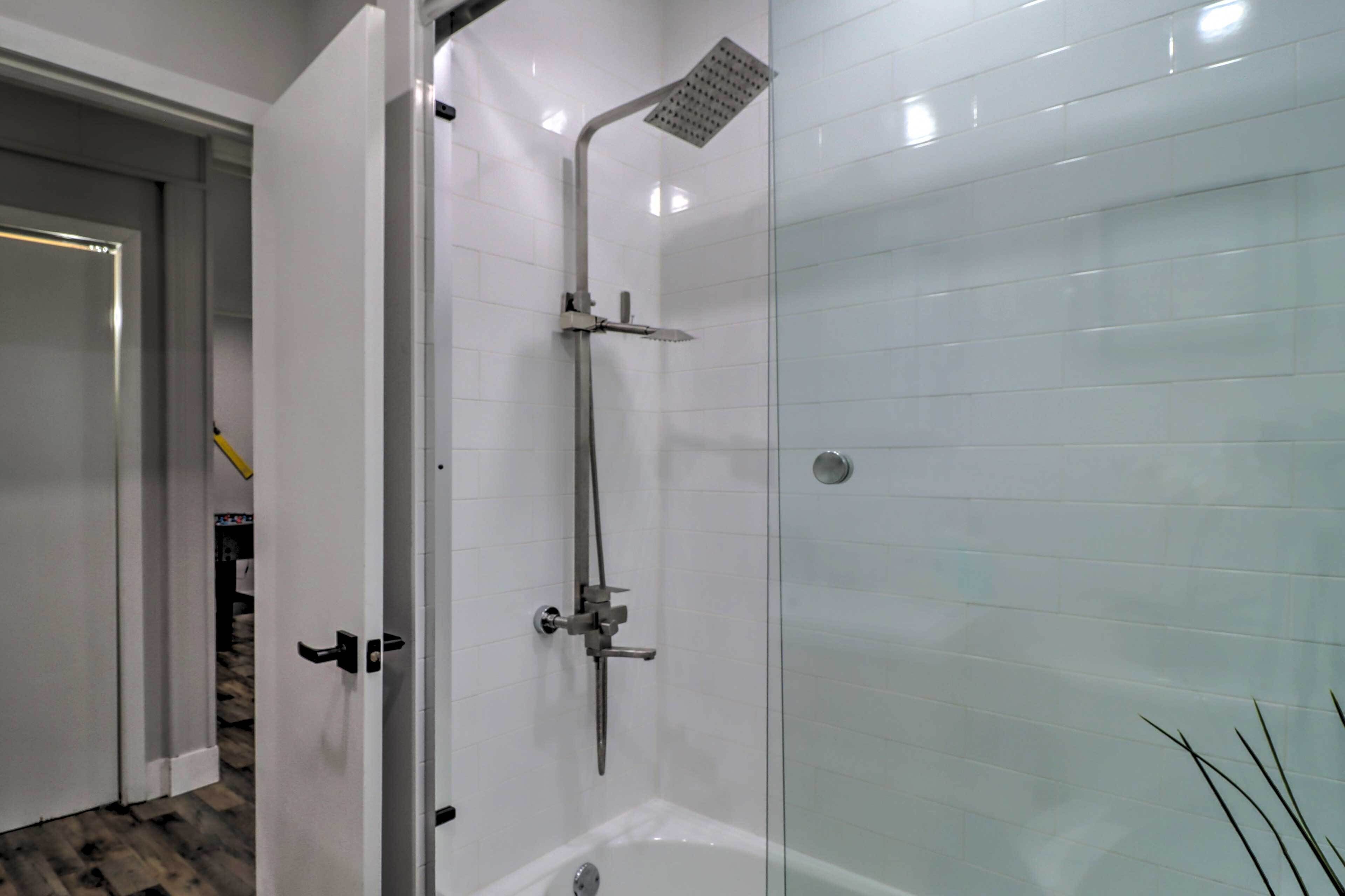 Ein modernes Badezimmer mit Duschkabine aus Glas, einer Badewanne und weißen Fliesen.