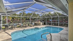 Ein überdachter Außenpool mit Glasveranda, Steinböden und einer Terrassenanlage mit Stühlen und Tisch.