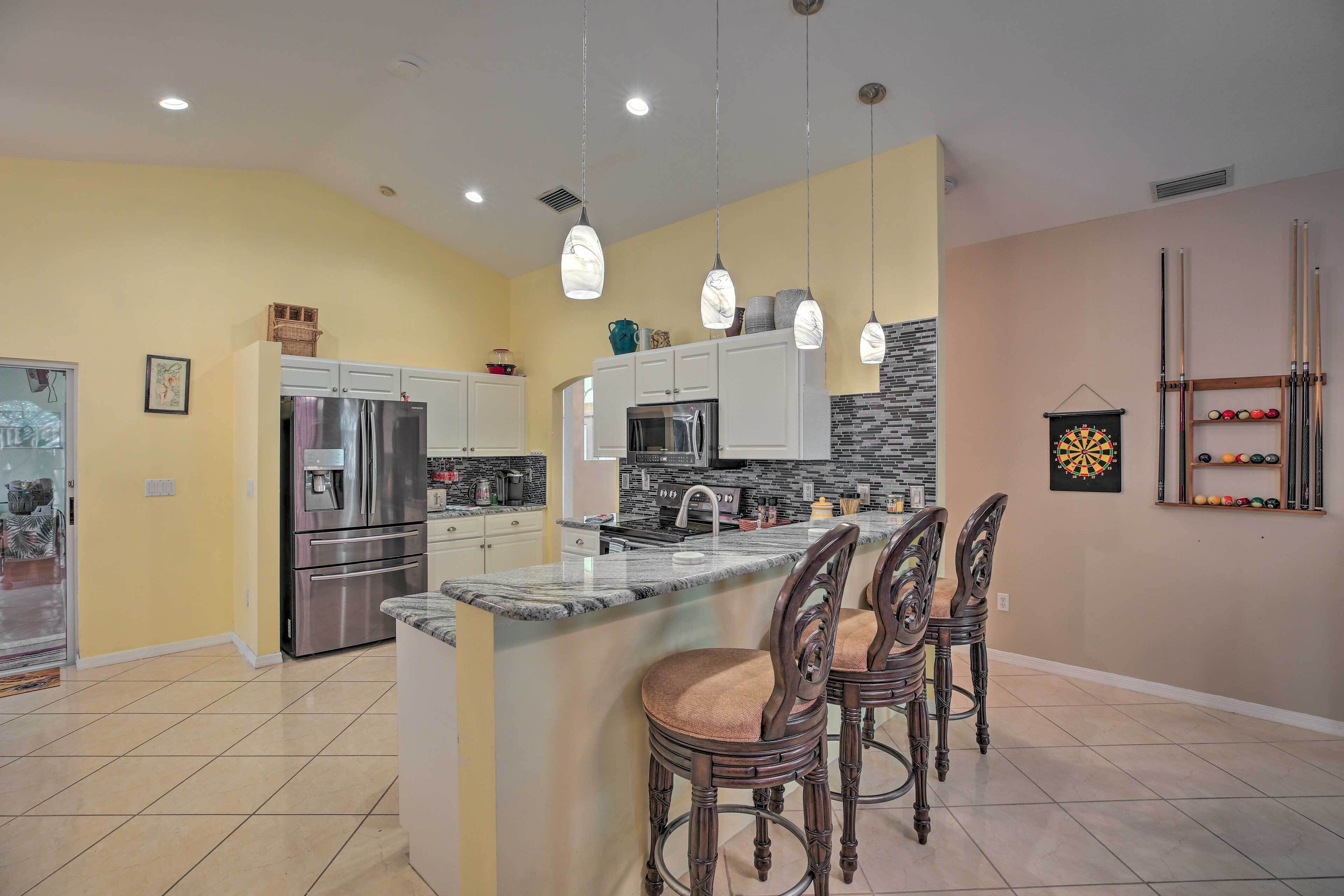 A modern kitchen with a central island, bar stools, and pendant lighting.