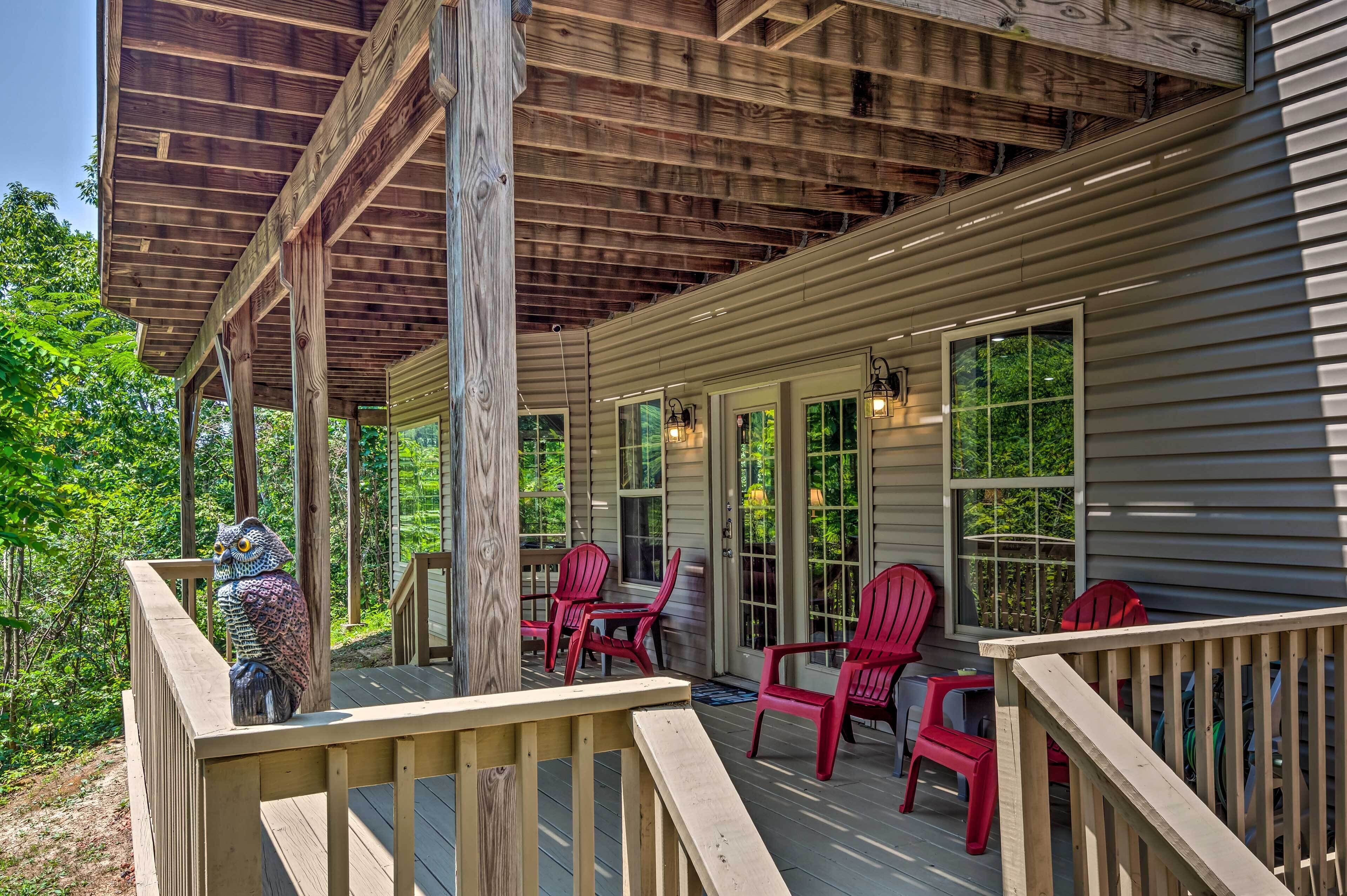 Une terrasse en bois avec des chaises rouges et une statue de hibou en bois.