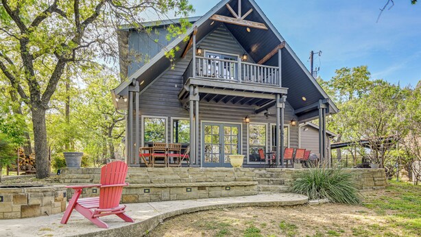 A wooden cabin with a balcony, stone steps, and outdoor seating.