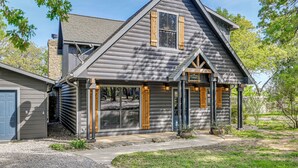 A log cabin with a gabled roof, a front porch, and a garage.