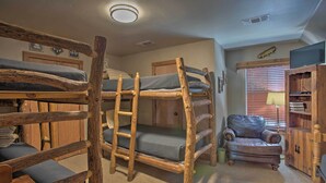 A bunk bed room with a ladder, a small armchair, and a wooden cabinet.