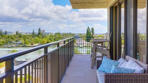 A balcony with a view of a river and cityscape, furnished with a sofa and chairs.