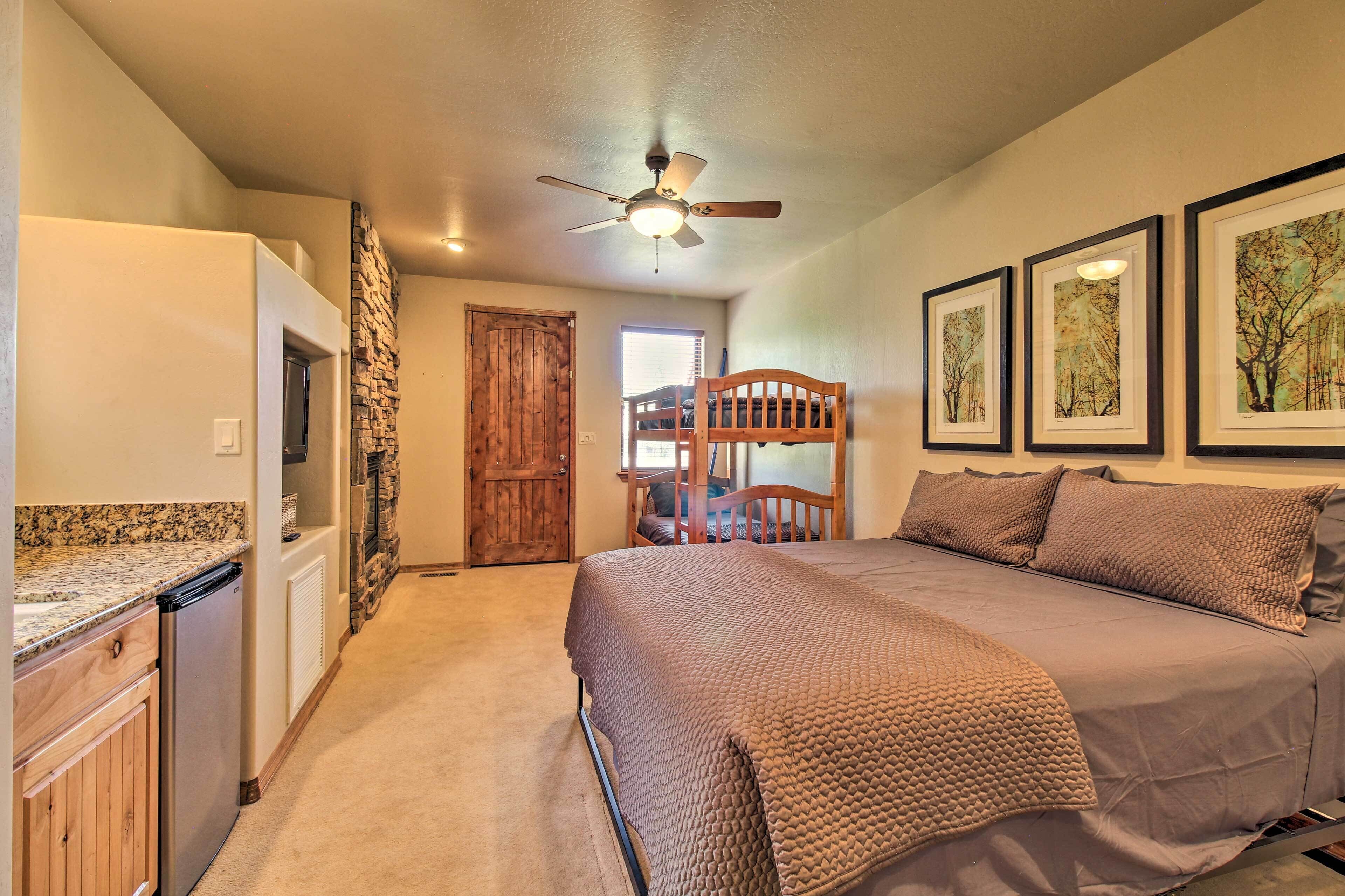 A bedroom with a bed, a ceiling fan, a wooden door, and a window.