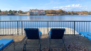 A waterfront view with two blue lounge chairs and a dock extending into the water. - Pool & Dock Access: Lakefront Hot Springs Condo! (Hot Springs)