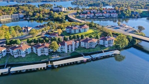 A lakeside residential area with multiple two-story houses, a dock, and a bridge connecting the properties. - Pool & Dock Access: Lakefront Hot Springs Condo! (Hot Springs)