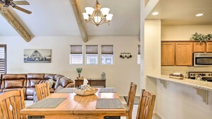 A dining area with a wooden table and chairs, a brown leather couch, and a kitchen with wooden cabinets and a microwave. - Deck & Game Room: Spacious Pinetop Cabin! (Pinetop)