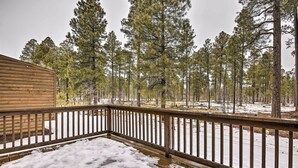 A wooden deck with a railing overlooking a snowy landscape with pine trees. - Deck & Game Room: Spacious Pinetop Cabin! (Pinetop)