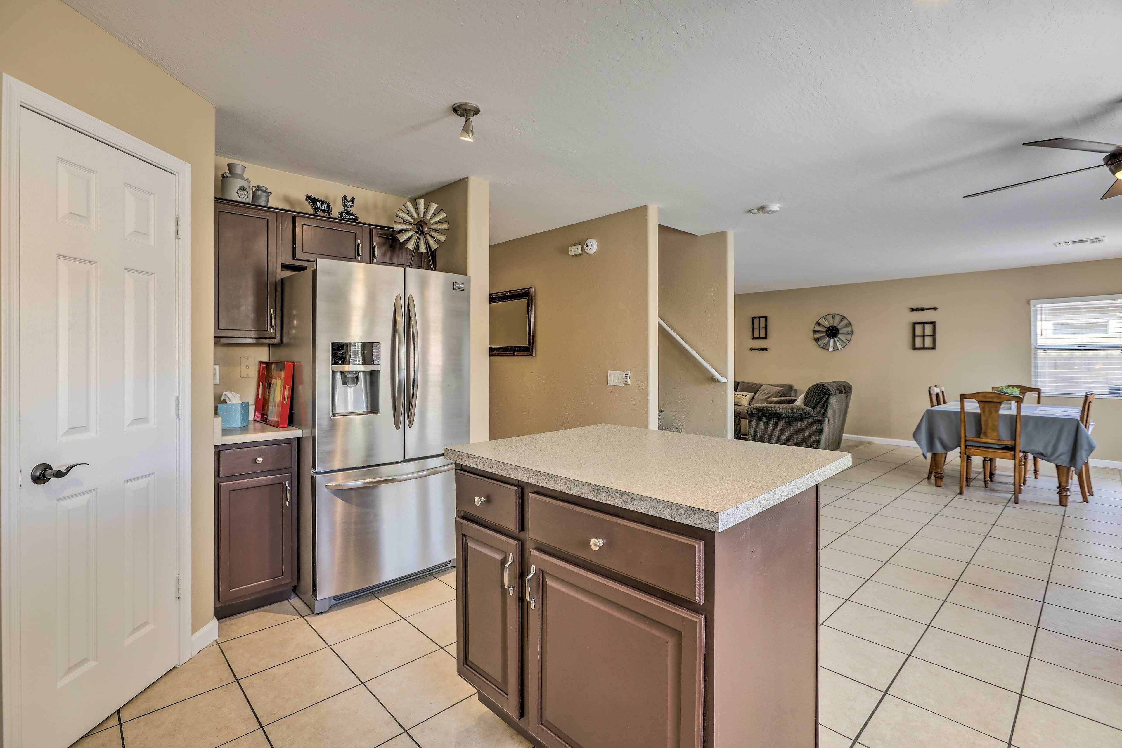 A kitchen with a stainless steel refrigerator, dark wooden cabinets, and a beige countertop.