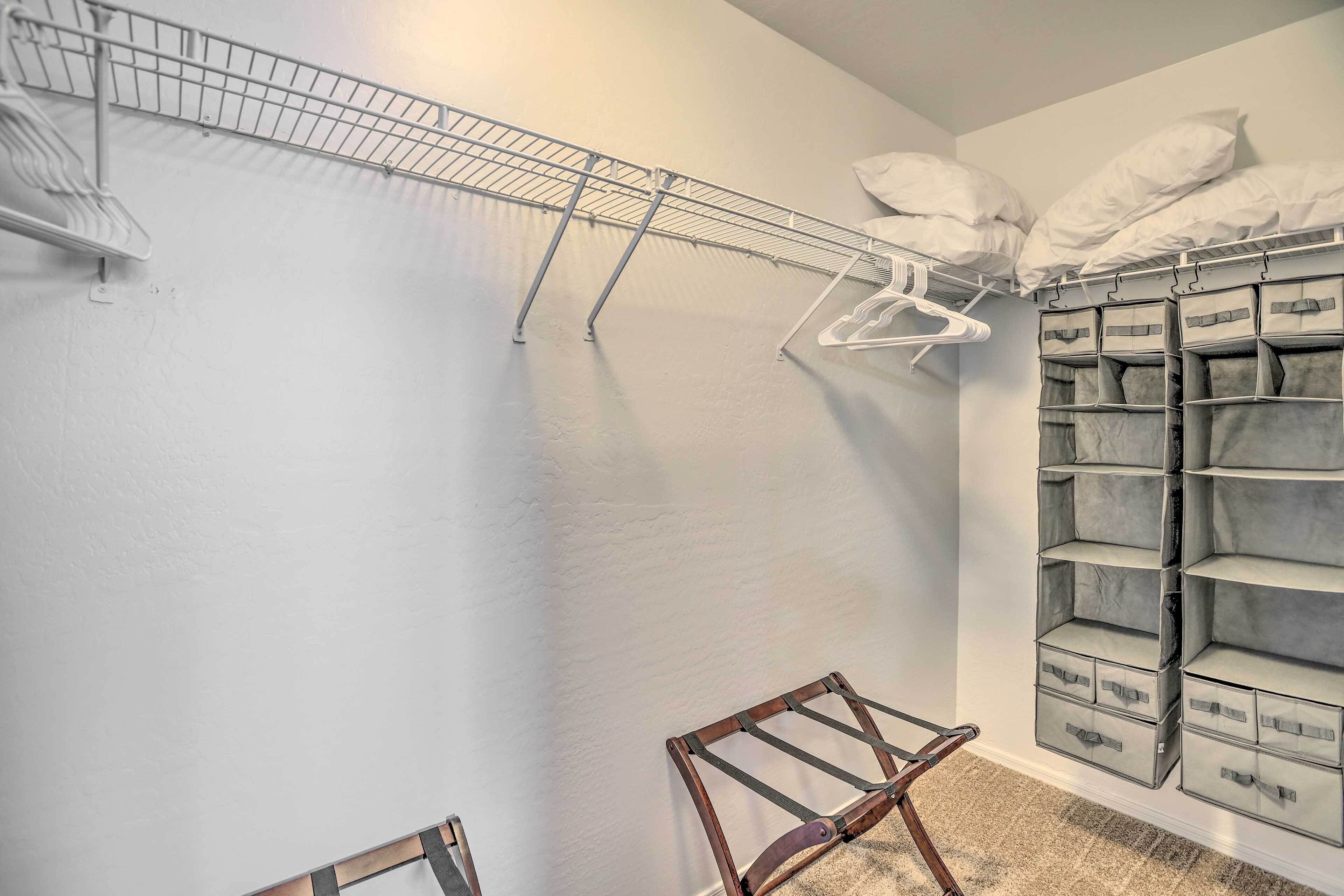 A room with a metal drying rack, a wooden chair, and storage boxes on the wall.