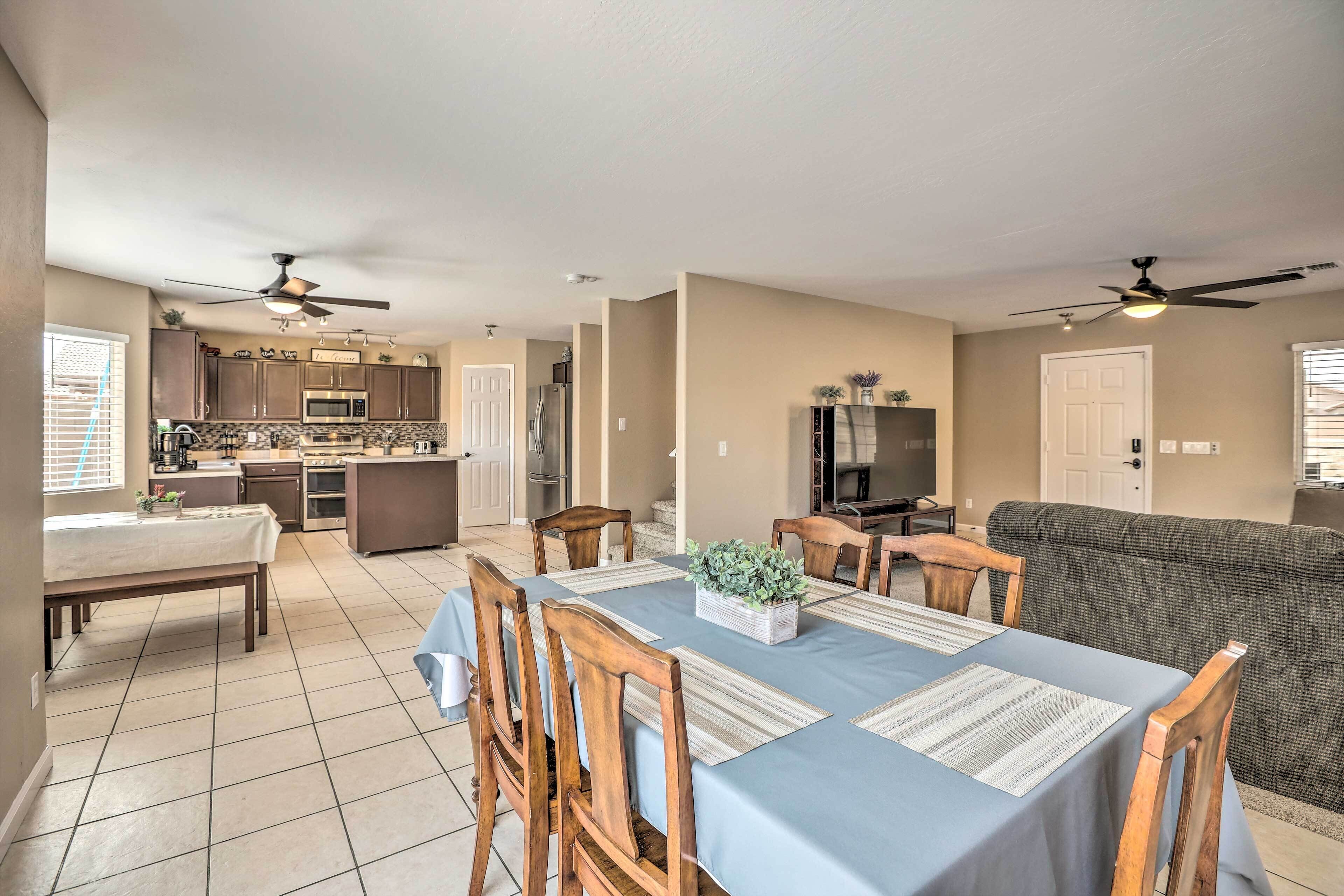 A spacious living area with a dining table, chairs, a sofa, and a kitchen in the background.