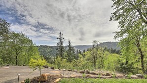 A campground with a paved area, surrounded by trees and a mountain backdrop.