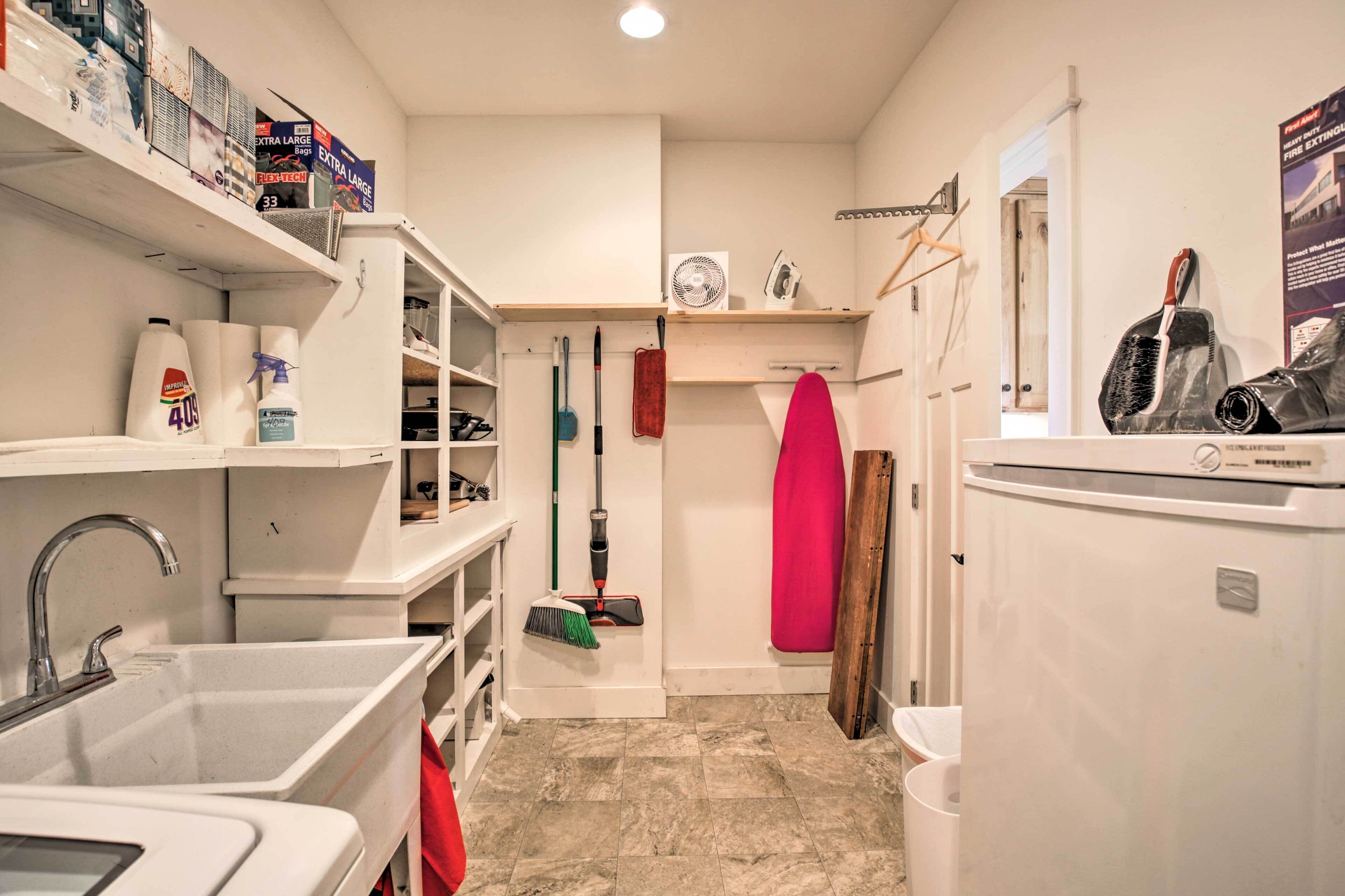 A compact kitchen with white cabinetry, a sink, a fan, and a refrigerator.