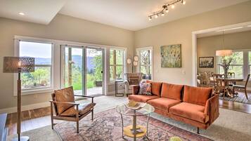 Relax in a spacious living area with a comfortable sofa, stylish armchair, and large windows offering views of the surrounding landscape.