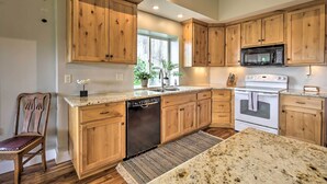 A kitchen with wooden cabinets, a dishwasher, a microwave, an oven, and a granite countertop.