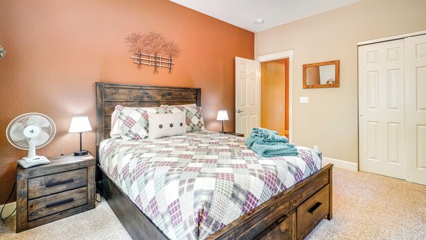 A bedroom with a wooden bed, two bedside tables with lamps, a ceiling fan, and a door to another room. - Hike + Explore: Graeagle Getaway w/ Furnished Deck (Blairsden-Graeagle)