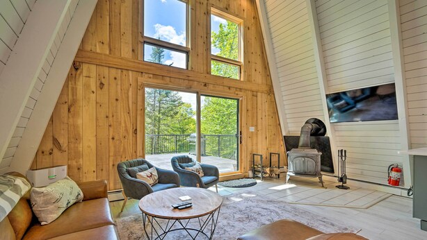 A spacious loft bedroom with a large skylight, a cozy seating area with leather sofas, and a fireplace. - Wilmington Chalet w/ Hot Tub < 8 Mi to Mount Snow! (Wilmington)