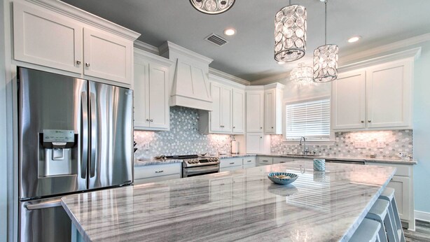 A modern kitchen with white cabinets, stainless steel appliances, a marble island, and pendant lighting. - Luxe Stilted Home w/ Kayaks: Walk to Beach (Dauphin Island)