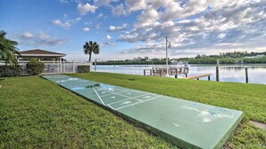 Un terrain de jeu de shuffleboard au bord d’un lac, avec un belvédère et un quai en arrière-plan.