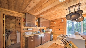 A wooden cabin kitchen with a wooden interior, a sink, cabinets, a microwave, and a stove. - Cozy Cottage on Cat Cove w/ Wraparound Deck! (Stonington)