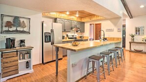 Une cuisine moderne dotée d’un îlot central, de tabourets de bar et d’un coin café.