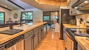 Une cuisine moderne dotée de meubles en bois, d’appareils électroménagers en acier inoxydable et d’un grand îlot central avec un lave-vaisselle.