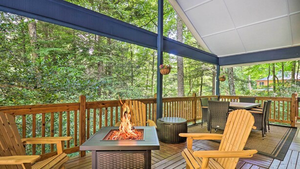 Une terrasse couverte avec un foyer, des chaises en bois et une table.