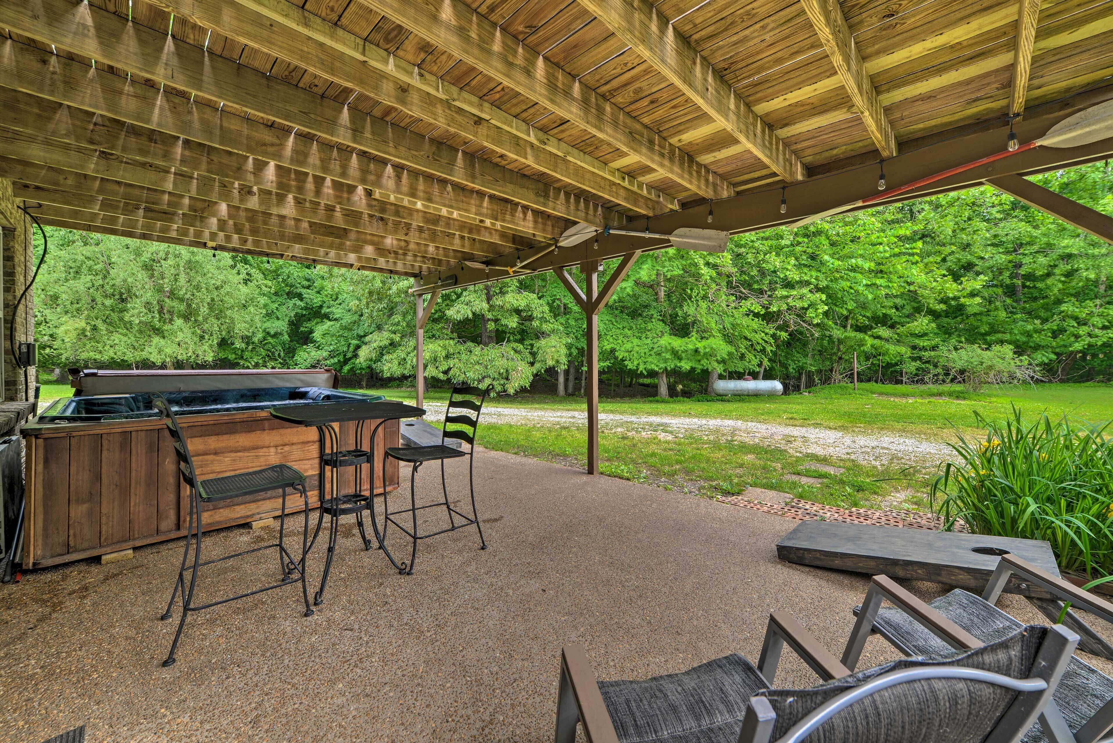 An outdoor patio with a grill, seating, and a view of the forest.