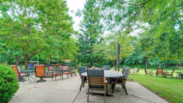 An outdoor patio area with a table and chairs, surrounded by trees and greenery. - Southeast Michigan Escape w/ Outdoor Fun (Adrian)