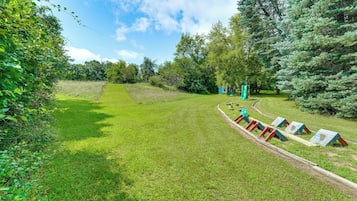 A grassy outdoor area with a playground and trees.
