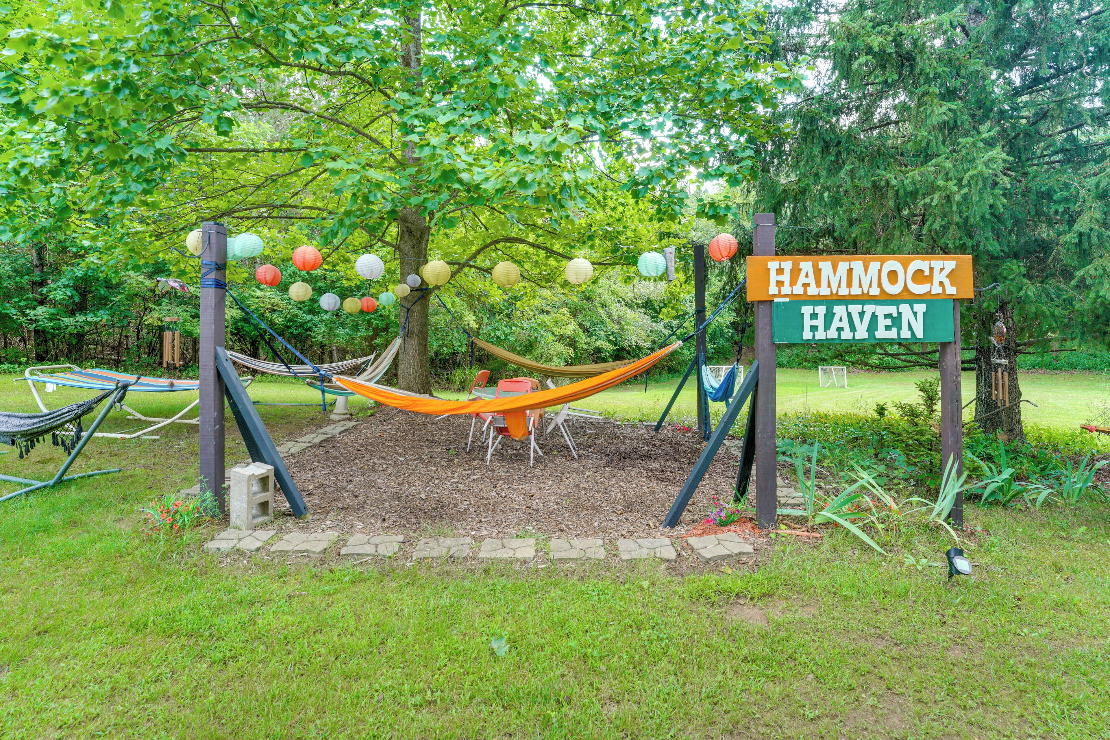Un hamac est installé sous un arbre dans un espace aménagé d’un parc, avec une pancarte indiquant : « HAVRE DE HAMACS ».