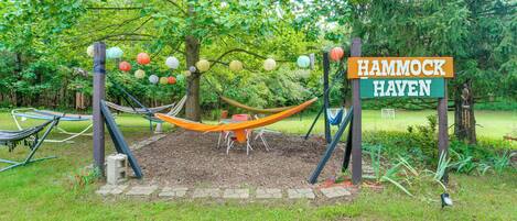 Un hamac est installé sous un arbre dans un espace aménagé d’un parc, avec une pancarte indiquant : « HAVRE DE HAMACS ».
