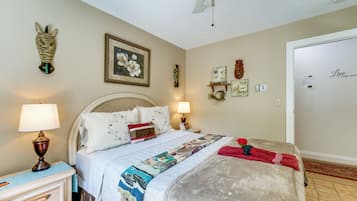 Un dormitorio con cama, lámparas de noche, un reloj de pared, un cuadro enmarcado y una puerta con un letrero.