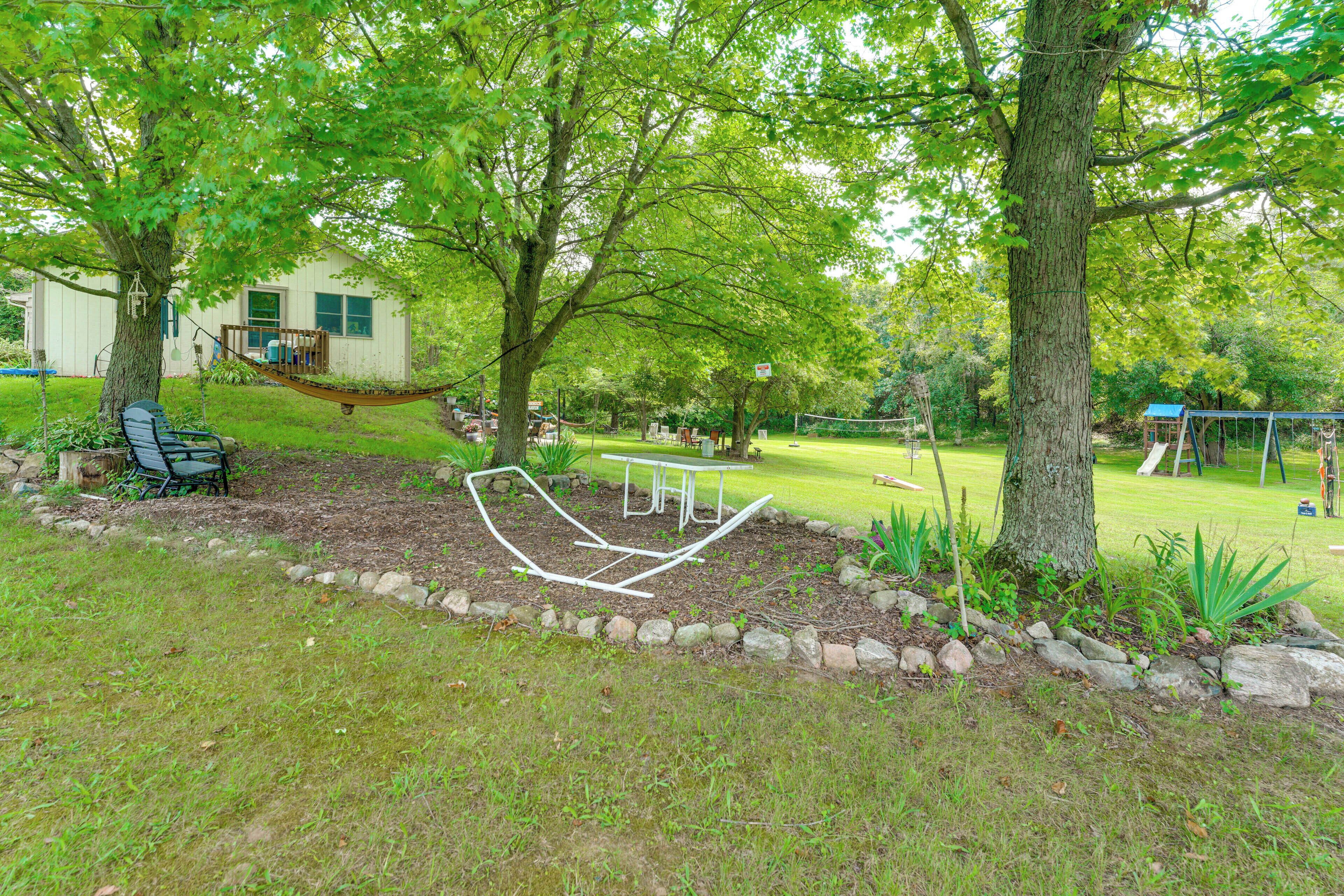 A backyard with a hammock, a swing set, and a picnic table.