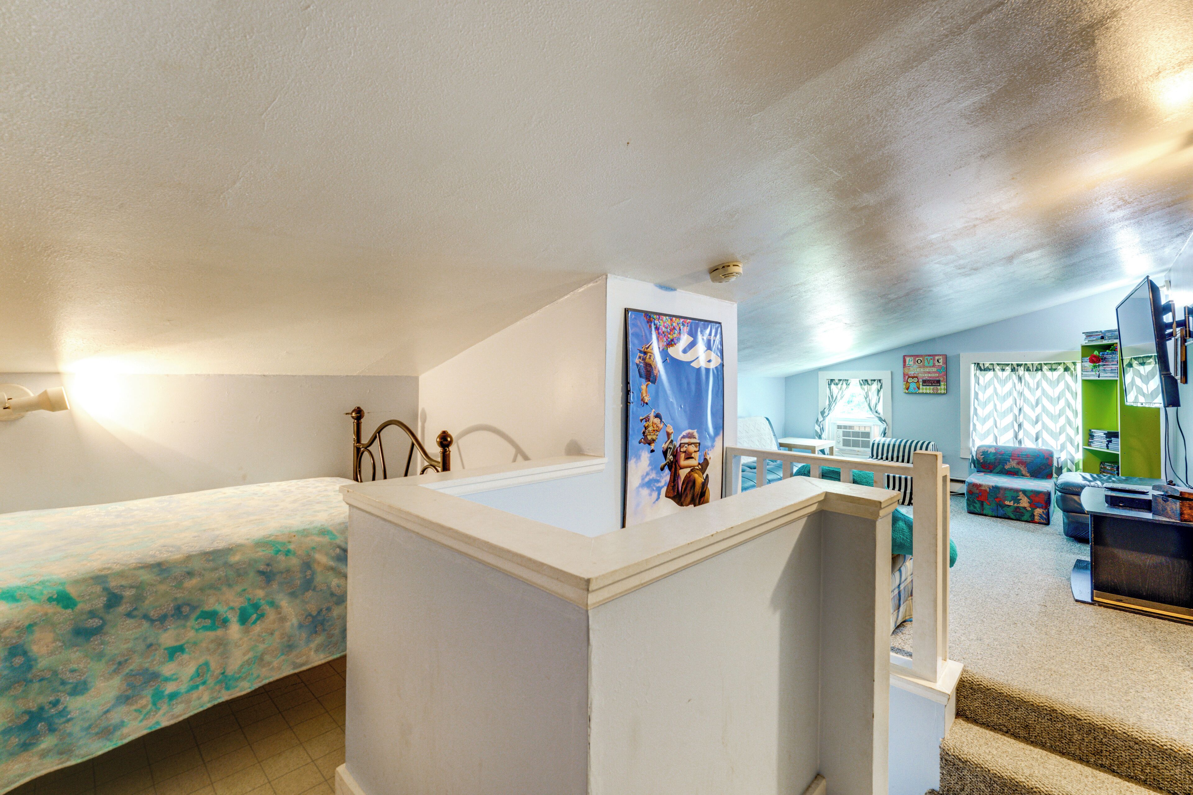 A room with a bed, a desk, a chair, and a small kitchenette area.