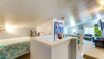 A room with a bed, a desk, a chair, and a small kitchenette area.