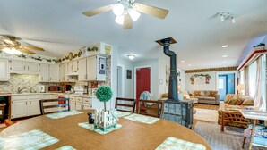 A spacious kitchen with white cabinets, a dining table with placemats, and a large wooden dining table. - Southeast Michigan Escape w/ Outdoor Fun (Adrian)