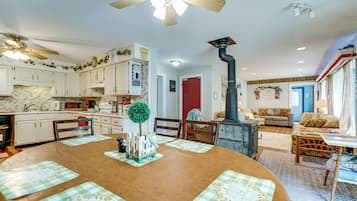 A spacious kitchen with white cabinets, a dining table with placemats, and a large wooden dining table.