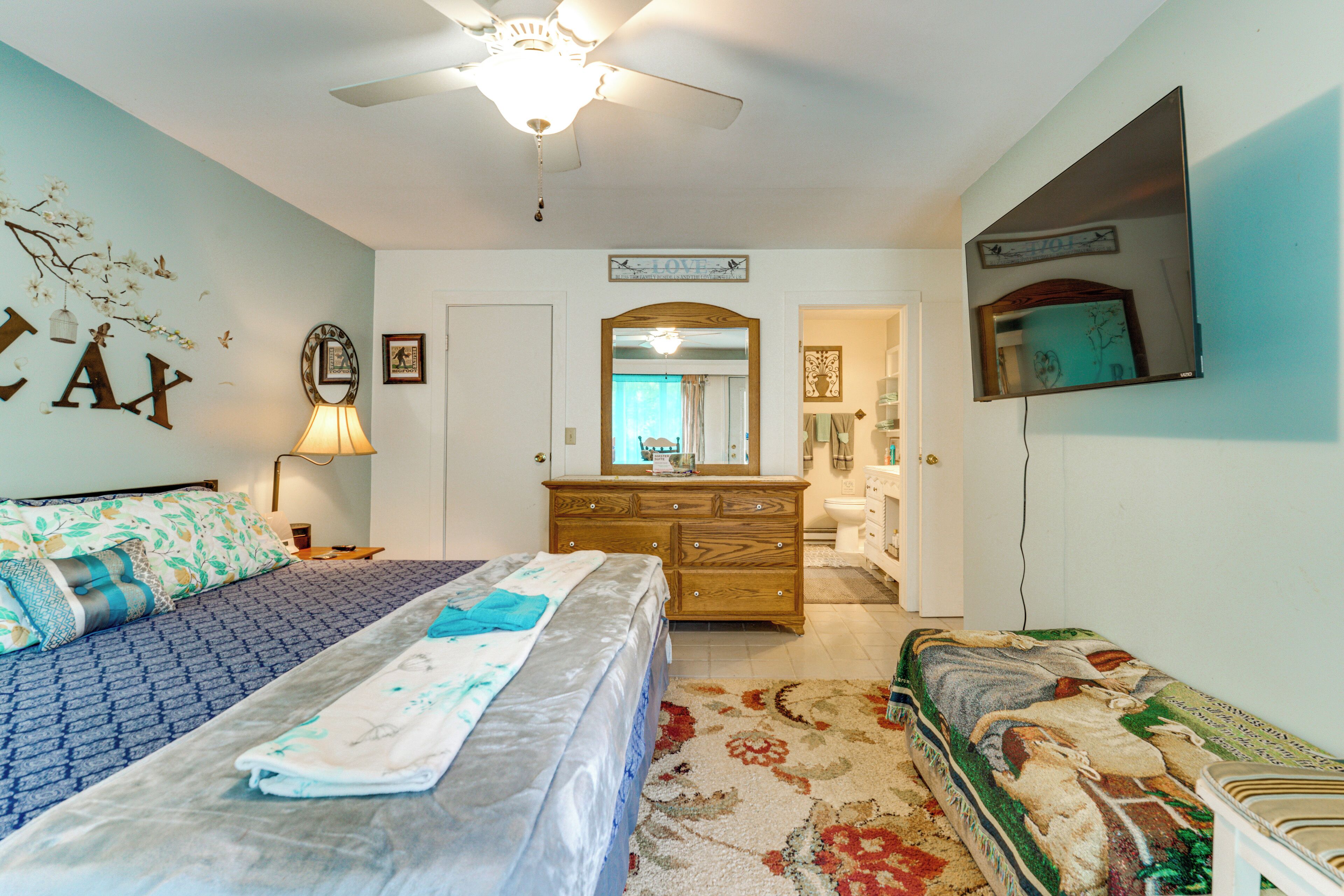 A bedroom with a bed, a dresser, a mirror, and a ceiling fan.