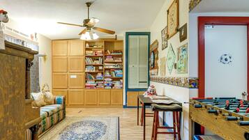 A room with a wooden cabinet, a ceiling fan, a bookshelf, a futsal table, and a patterned rug.