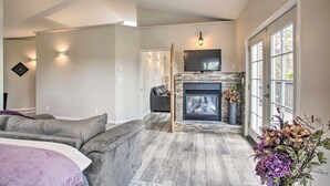 Una sala de estar moderna con chimenea, sofás grises y un ventanal grande.