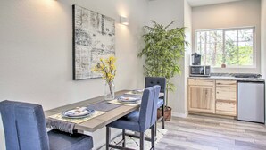 Un comedor con una mesa larga, sillas, un jarrón con flores y una obra de arte colgada en la pared.