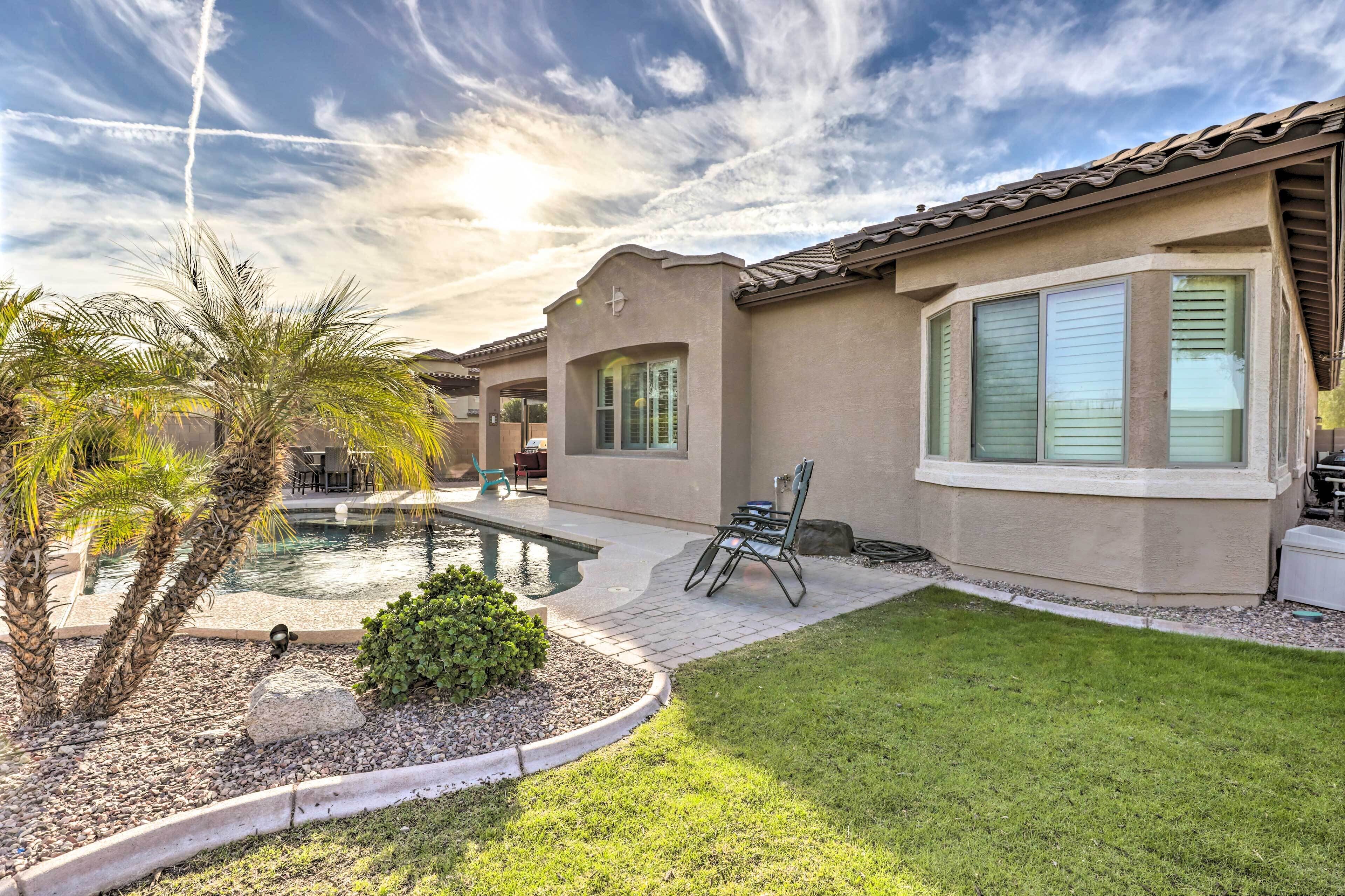 A residential property with a swimming pool, patio furniture, and a well-maintained lawn.