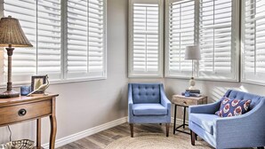 A room with a blue armchair, a small round table, a lamp, and a chair. - Goodyear Home w/ Pool: Near Golf & Ballpark! (Goodyear)