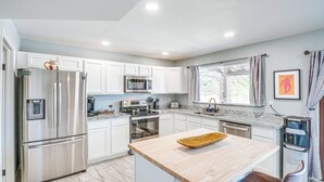 A modern kitchen with white cabinets, stainless steel appliances, a wooden island, and a window with curtains. - 'bear Canyon Casa' - Tucson Home Base w/ Mtn Views (Tucson)