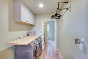 A laundry area with a washing machine, dryer, and wooden counter.