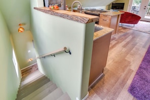 A kitchen with a granite countertop, a wooden island, and a red chair.