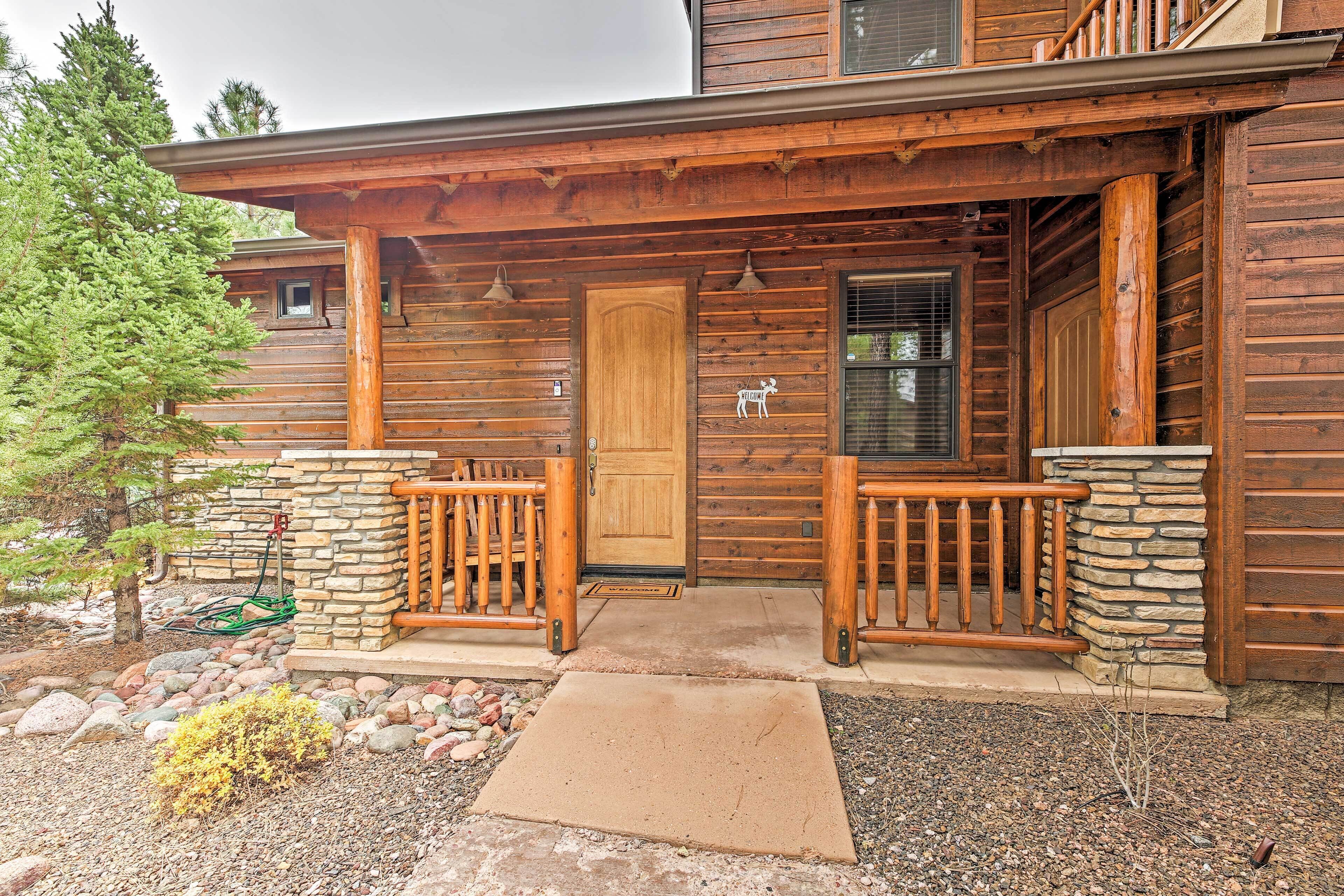 A wooden cabin with a porch, stone steps, and a wooden door.